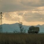 Ciężarówki na wiejskiej drodze o zmierzchu wśród słupów energetycznych