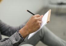 Jak prowadzić dziennik rozwoju osobistego w notatniku papierowym: praktyczny przewodnik krok po kroku Dorosła osoba pisze ołówkiem w papierowym dzienniku rozwoju osobistego