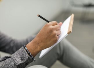Jak prowadzić dziennik rozwoju osobistego w notatniku papierowym: praktyczny przewodnik krok po kroku Dorosła osoba pisze ołówkiem w papierowym dzienniku rozwoju osobistego