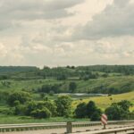 Pomarańczowa ciężarówka na autostradzie wśród zielonych pagórków