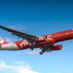 Samolot AirAsia lecący wysoko na tle czystego, błękitnego nieba