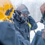 Strażacy w maskach ochronnych omawiają akcję w ośnieżonym lesie