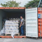 Dwóch mężczyzn załadowuje towar do kontenera transportowego w Ipoh