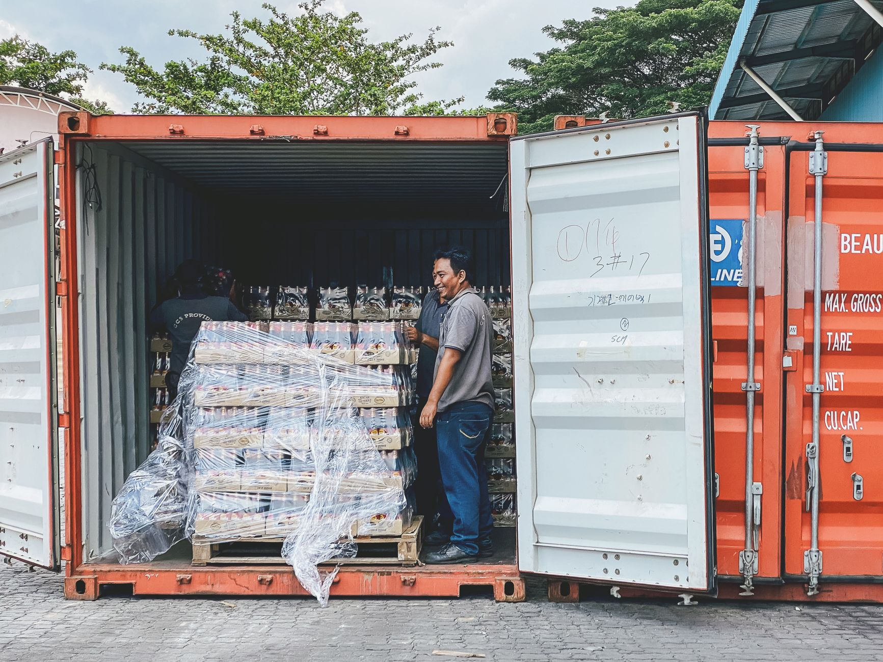 Dwóch mężczyzn załadowuje towar do kontenera transportowego w Ipoh