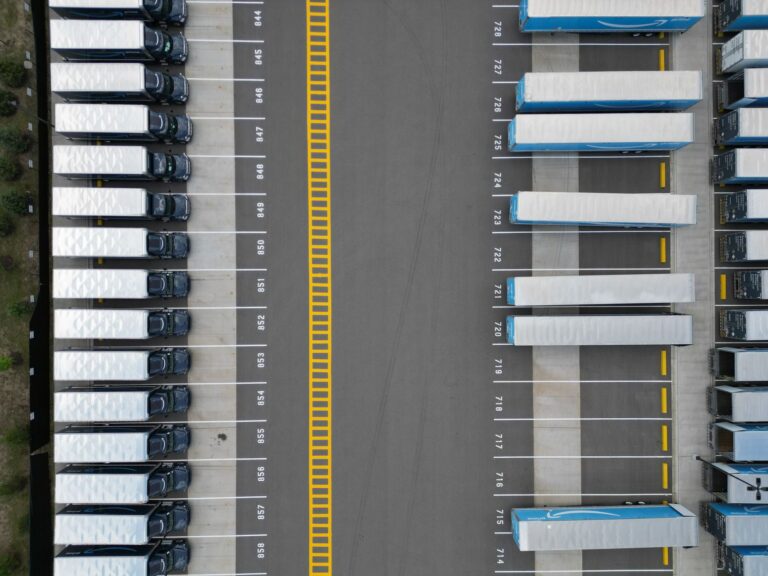 Ciężarówki ustawione w rzędach na parkingu logistycznym widziane z góry