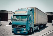 Przestój ciężarówki na załadunku – jak legalnie naliczyć i wyegzekwować rekompensatę? Niebieska ciężarówka Volvo zaparkowana przed magazynem przemysłowym